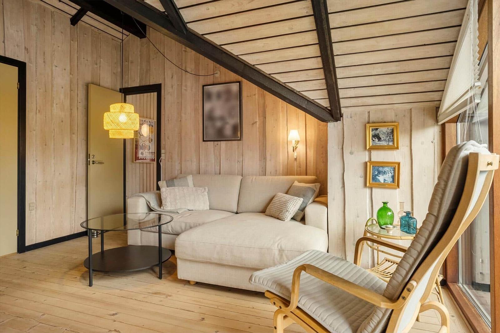 Wohnzimmer mit Sofa, Sessel und Holzwandverkleidung