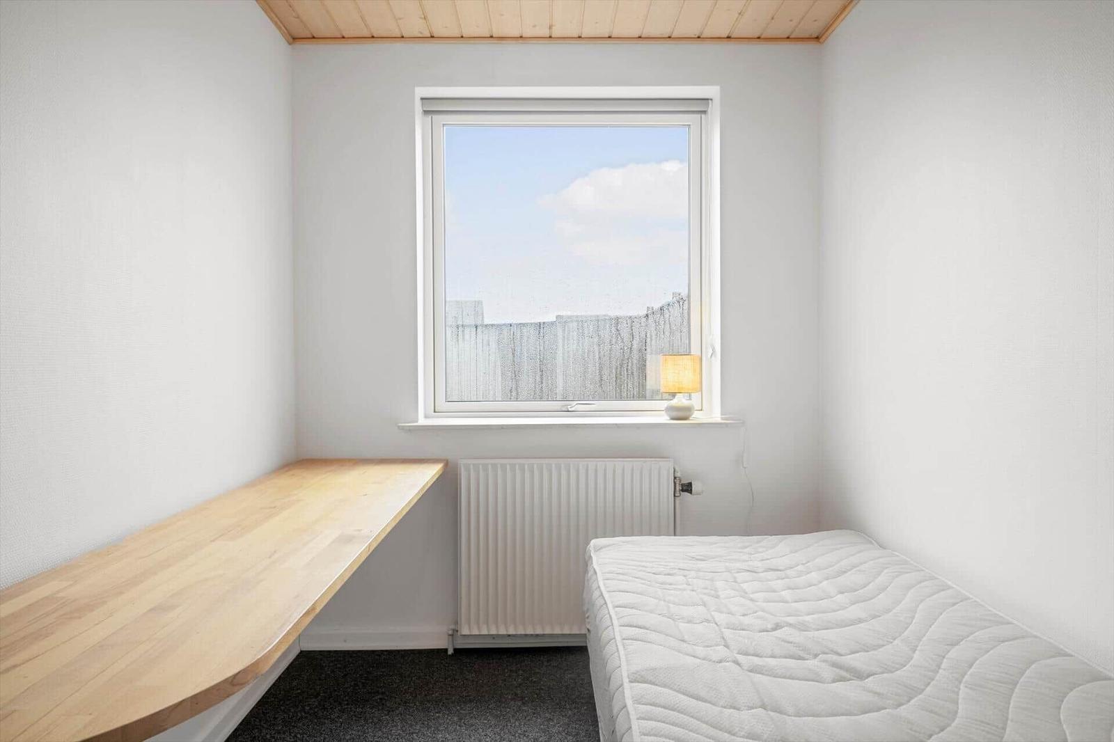 Ein Schlafzimmer mit Bett, Schreibtisch und Fenster.