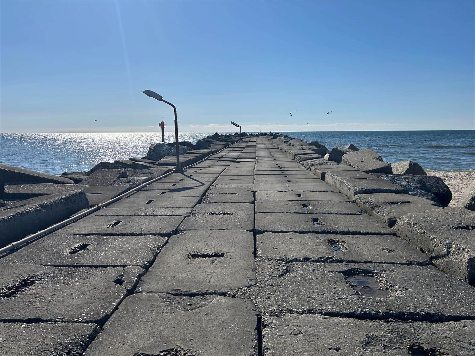 Steinpflasterweg führt über das Wasser zu einem Leuchtturm.