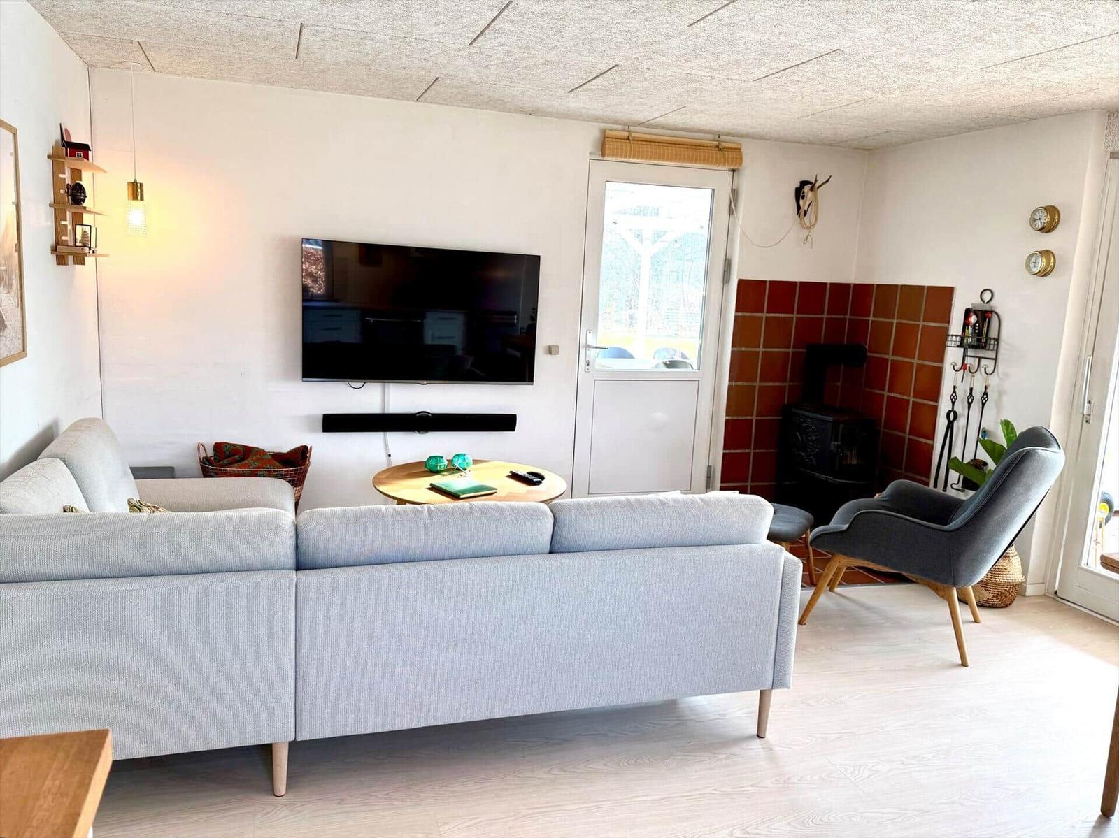 Wohnzimmer mit Sofa, Fernseher und Kamin