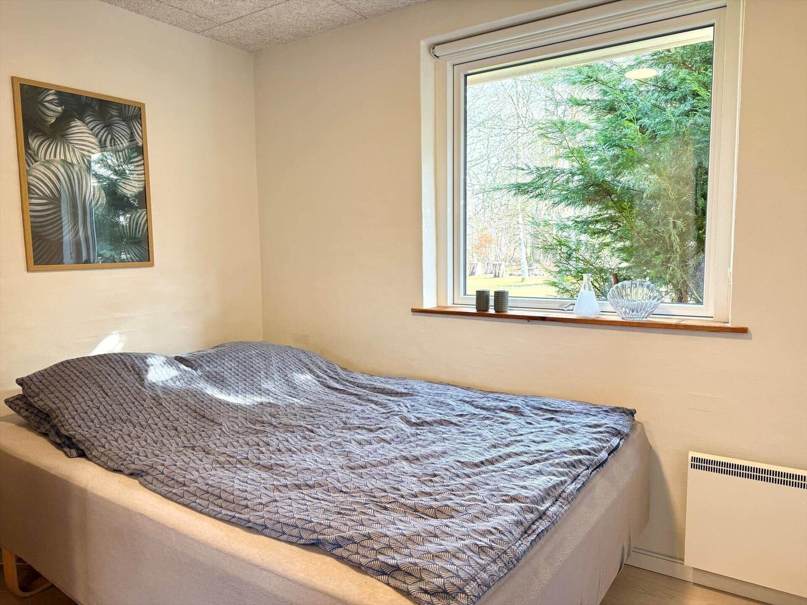 Ein Schlafzimmer mit Bett, Fenster und Wandbild.