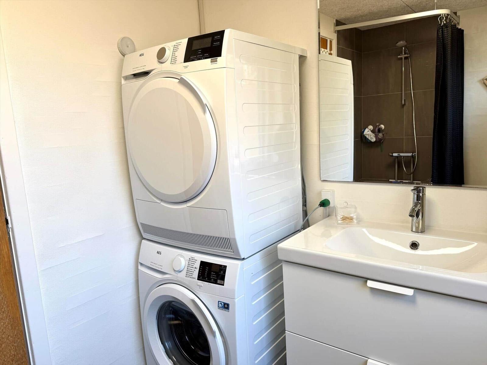 Waschmaschine und Trockner stehen im Bad. Spiegel und Waschbecken sind vorhanden.