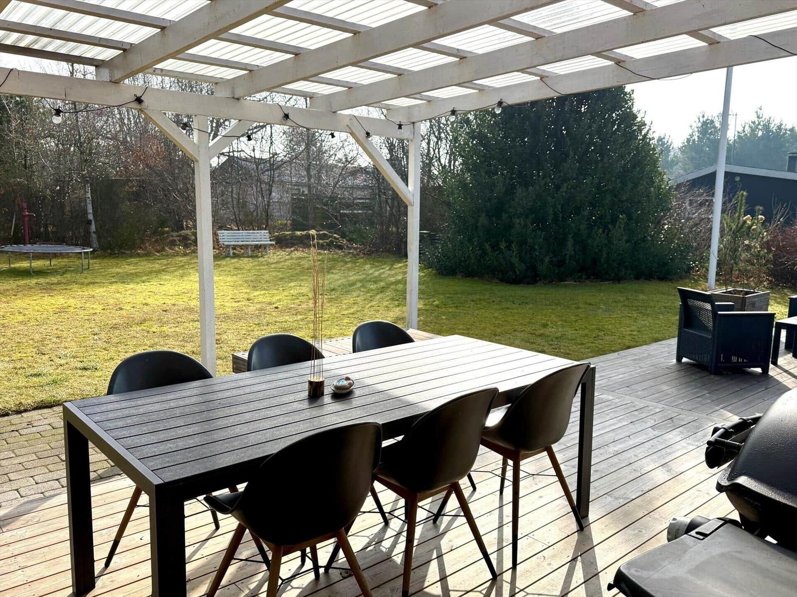 Terrasse mit Tisch und Stühlen unter Dach