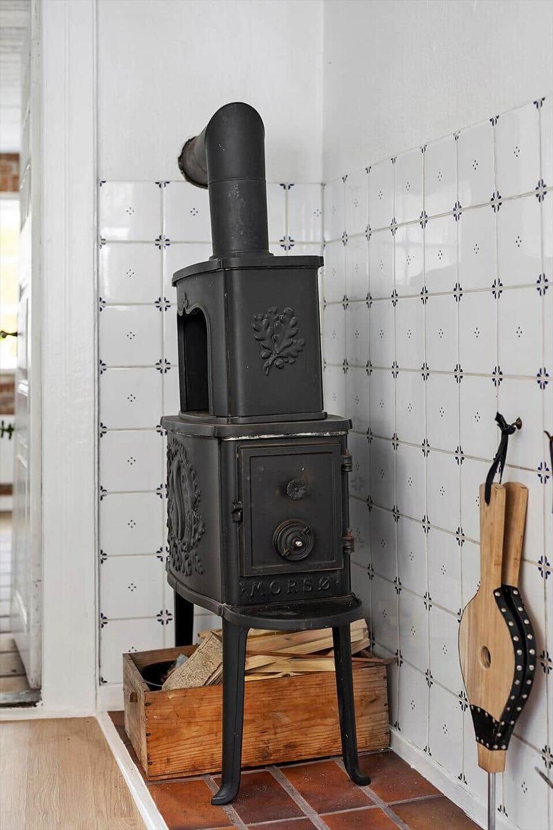 Black stove with wood box and tiled wall