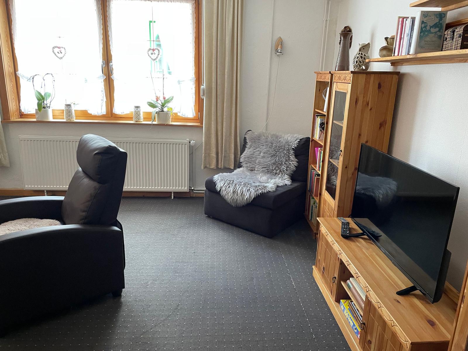 Wohnzimmer mit Schränken und Schlafsesselp