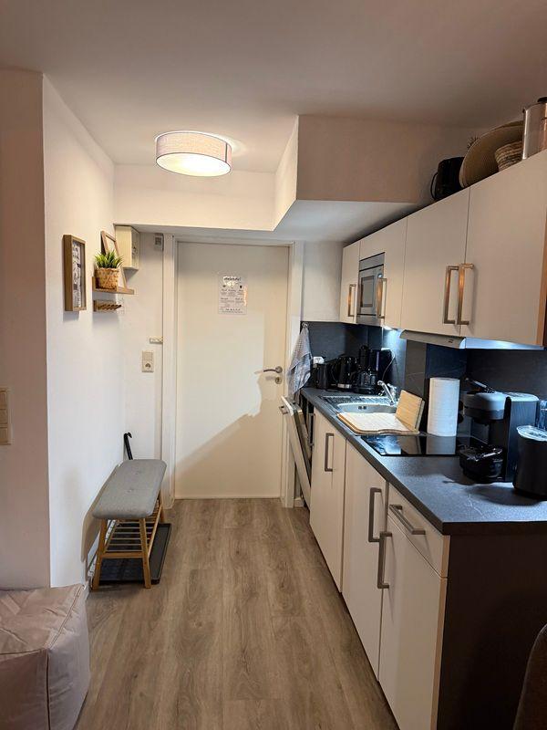 Kitchen with worktop, sink, and cabinets. Hallway with bench and door.