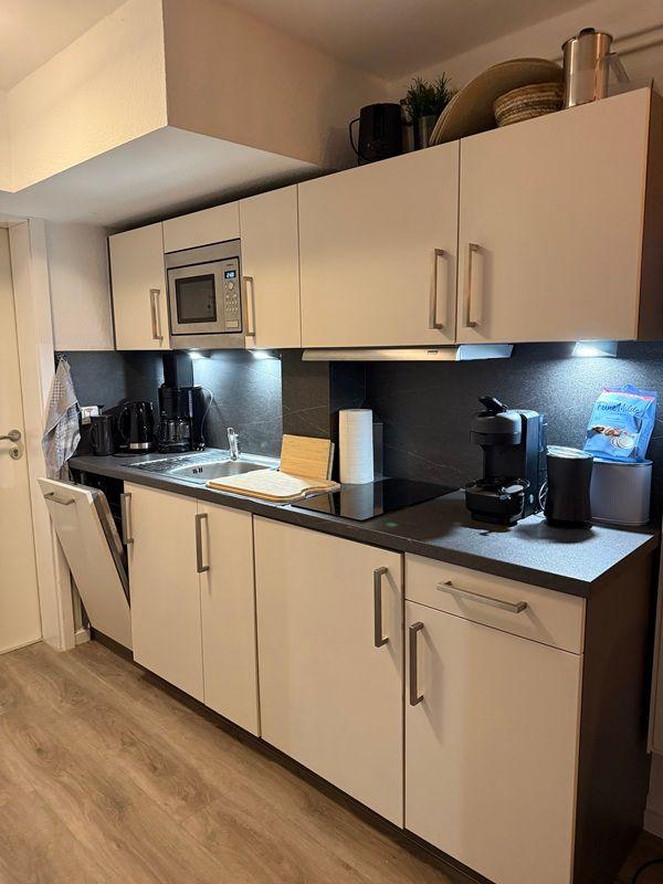 Kitchen with white cabinets, dark countertop, and built-in microwave.