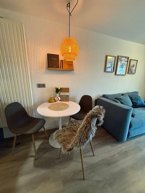 Dining area with round table, chairs, and sofa. Pendant lamp and wall art.