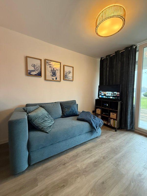 Living room with sofa, TV, and wooden floor.