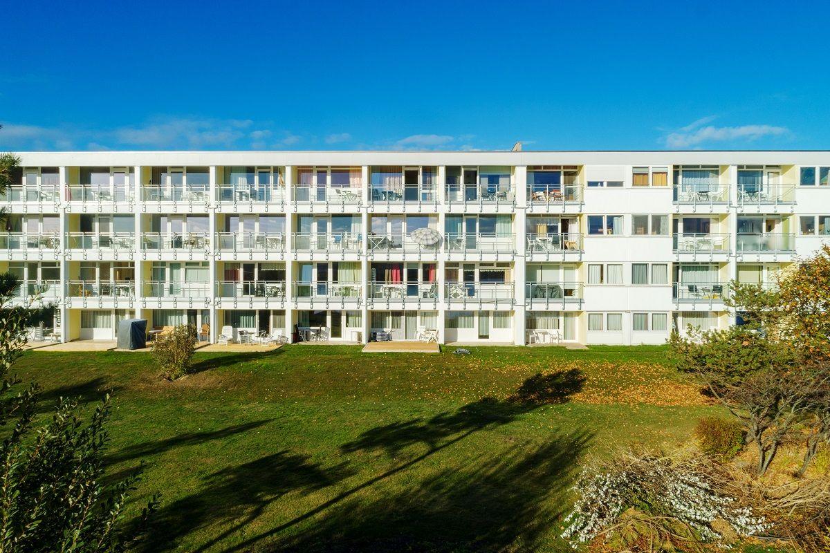 Modern apartment building with balconies and lawn in front.