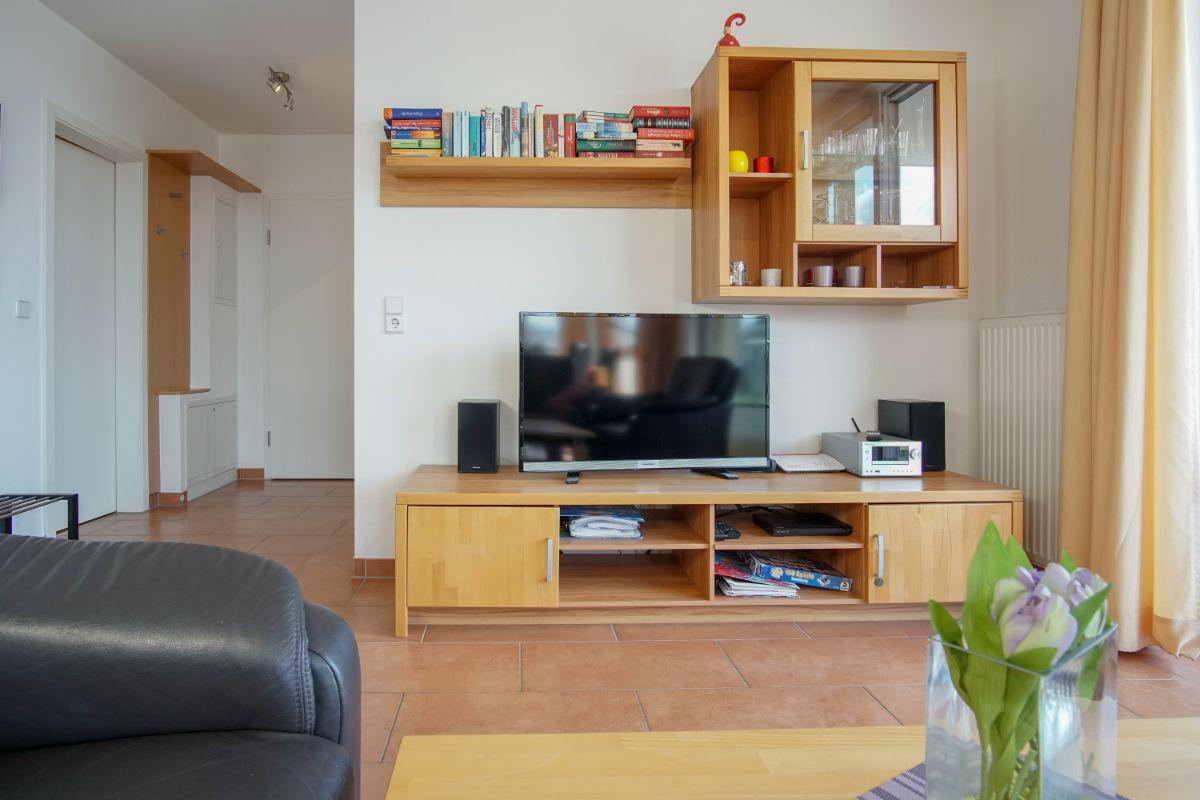Wohnzimmer mit Fernseher, Holzmöbel und Bücherregal.