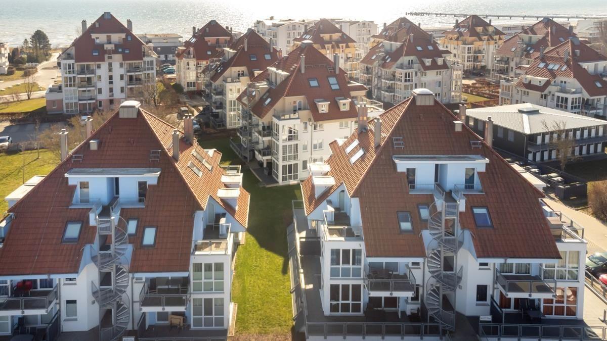 Meerfront-Apartments mit roten Dächern und Balkonen.