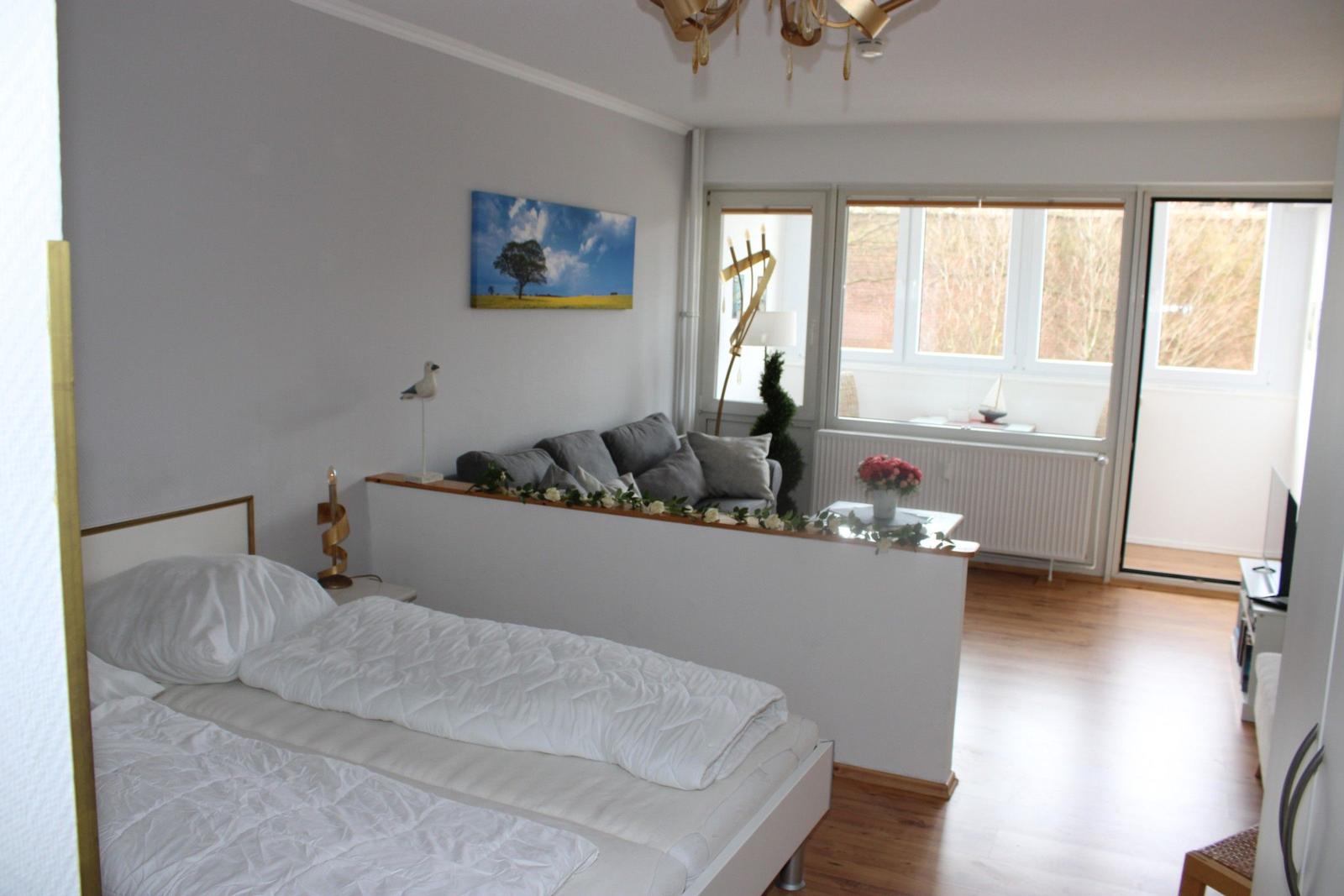 Schlafzimmer mit Bett und Sitzbereich. Fenster mit Blick nach draußen.