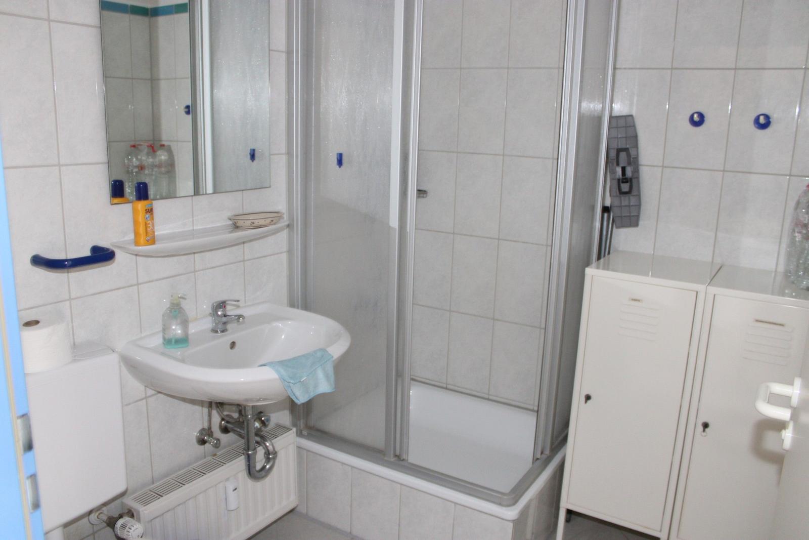 Badezimmer mit Dusche, Waschbecken und Spiegel