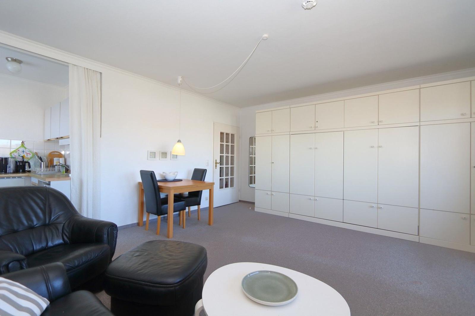 Wohnzimmer mit Esstisch, Sofa und integrierten Schränken.