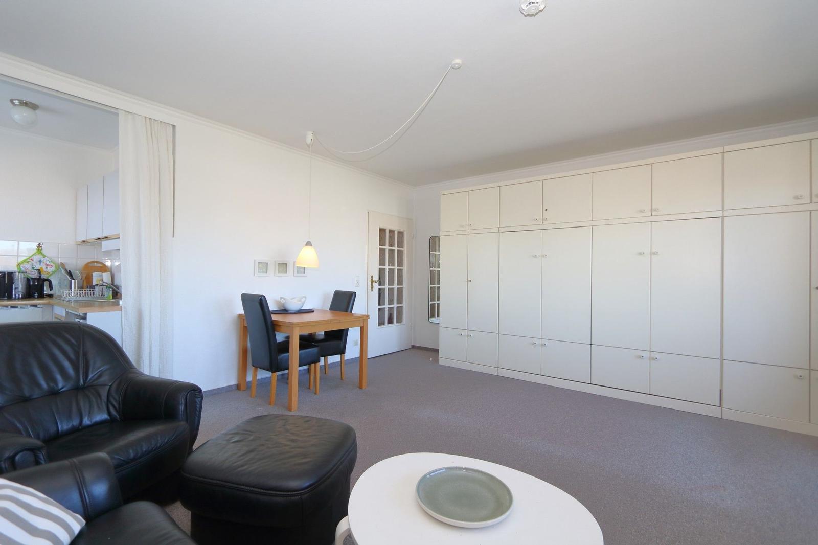 Wohnbereich mit Ledersofa, Esstisch und großen Schränken.