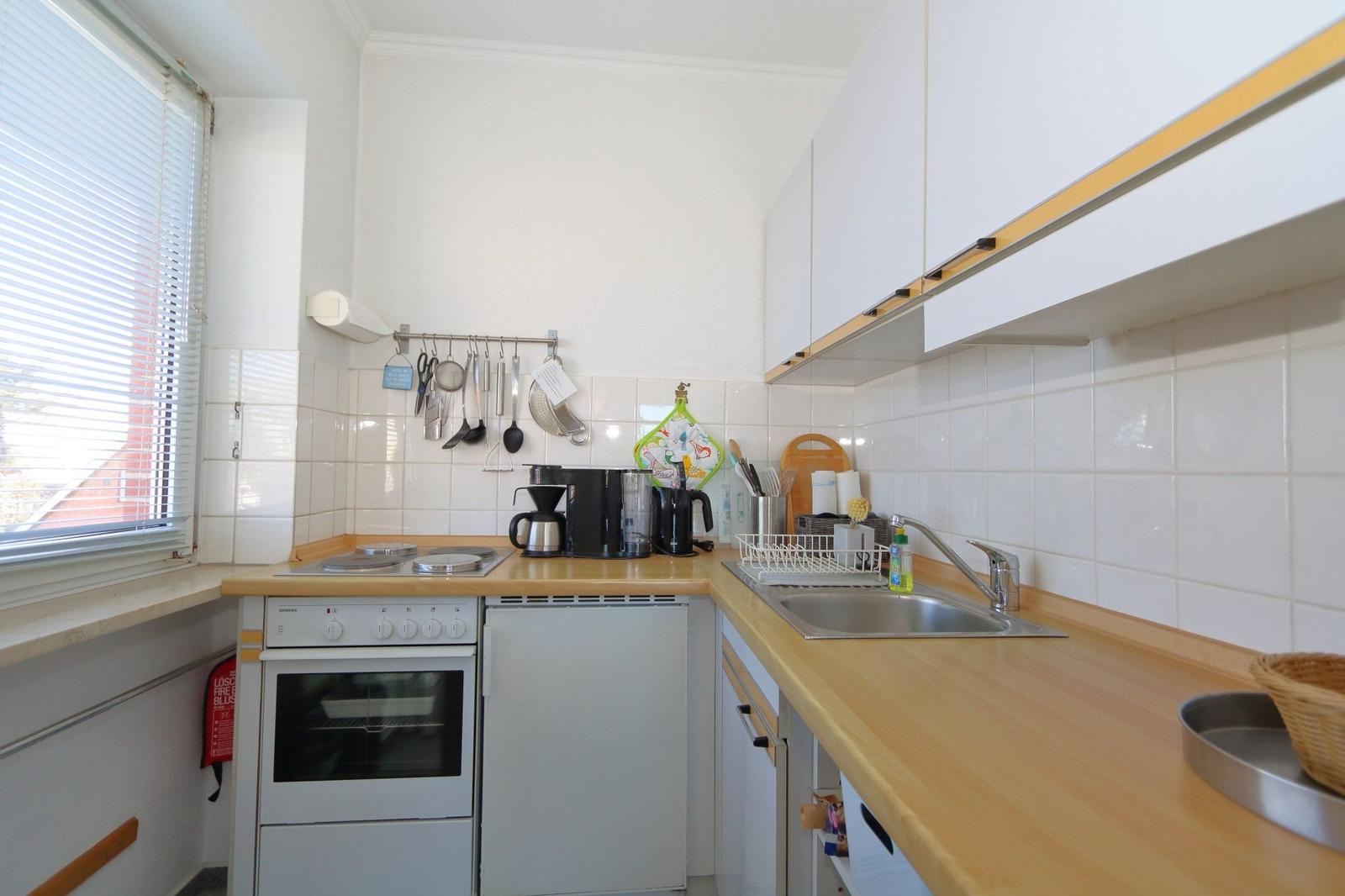 Küche mit Arbeitsplatte, Spüle, Herd und Küchenutensilien.