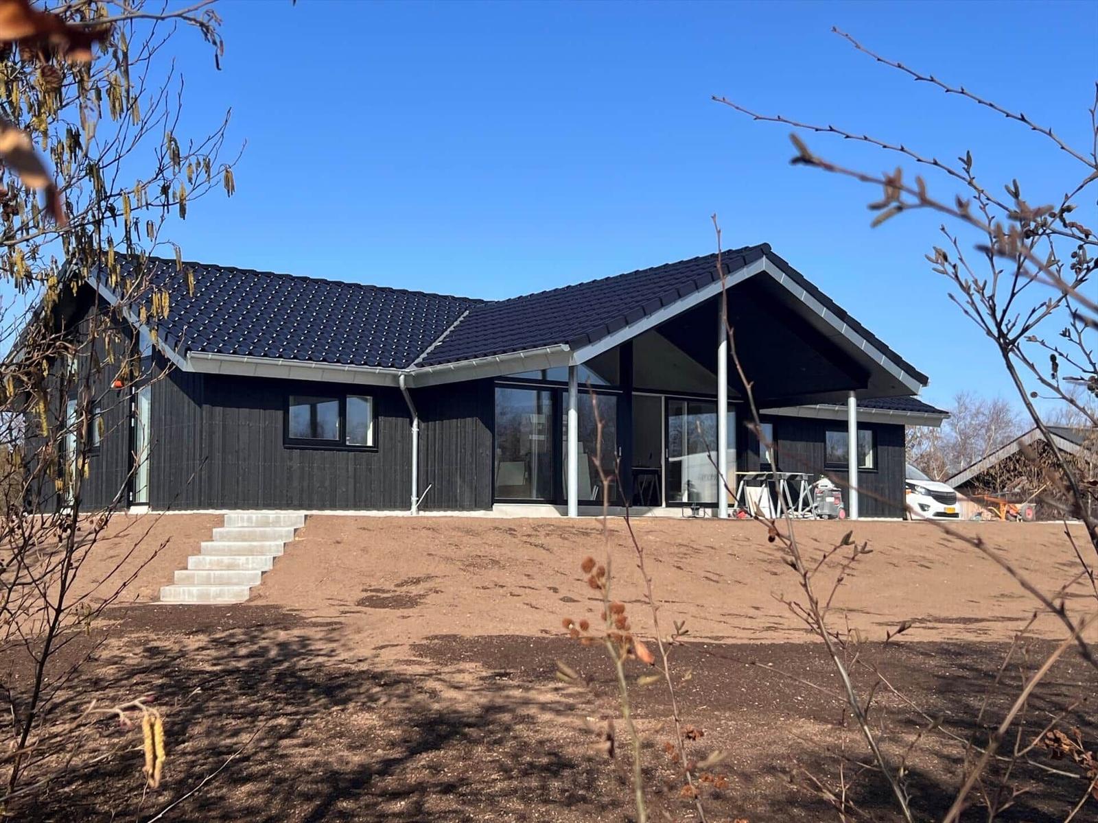 Moderne Holzhütte mit großem Glasbereich und schwarzem Dach