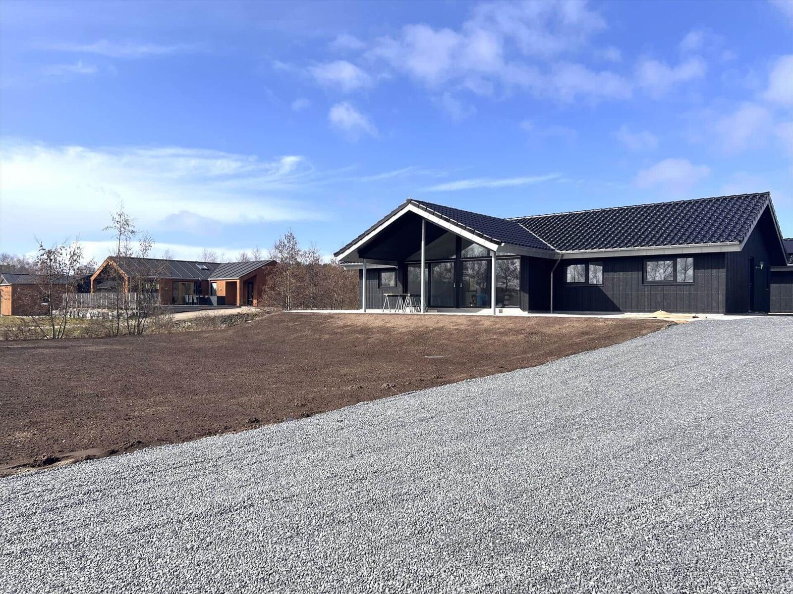 Modernes Haus mit großem Glasbereich und Steinweg. Im Hintergrund weitere Häuser.