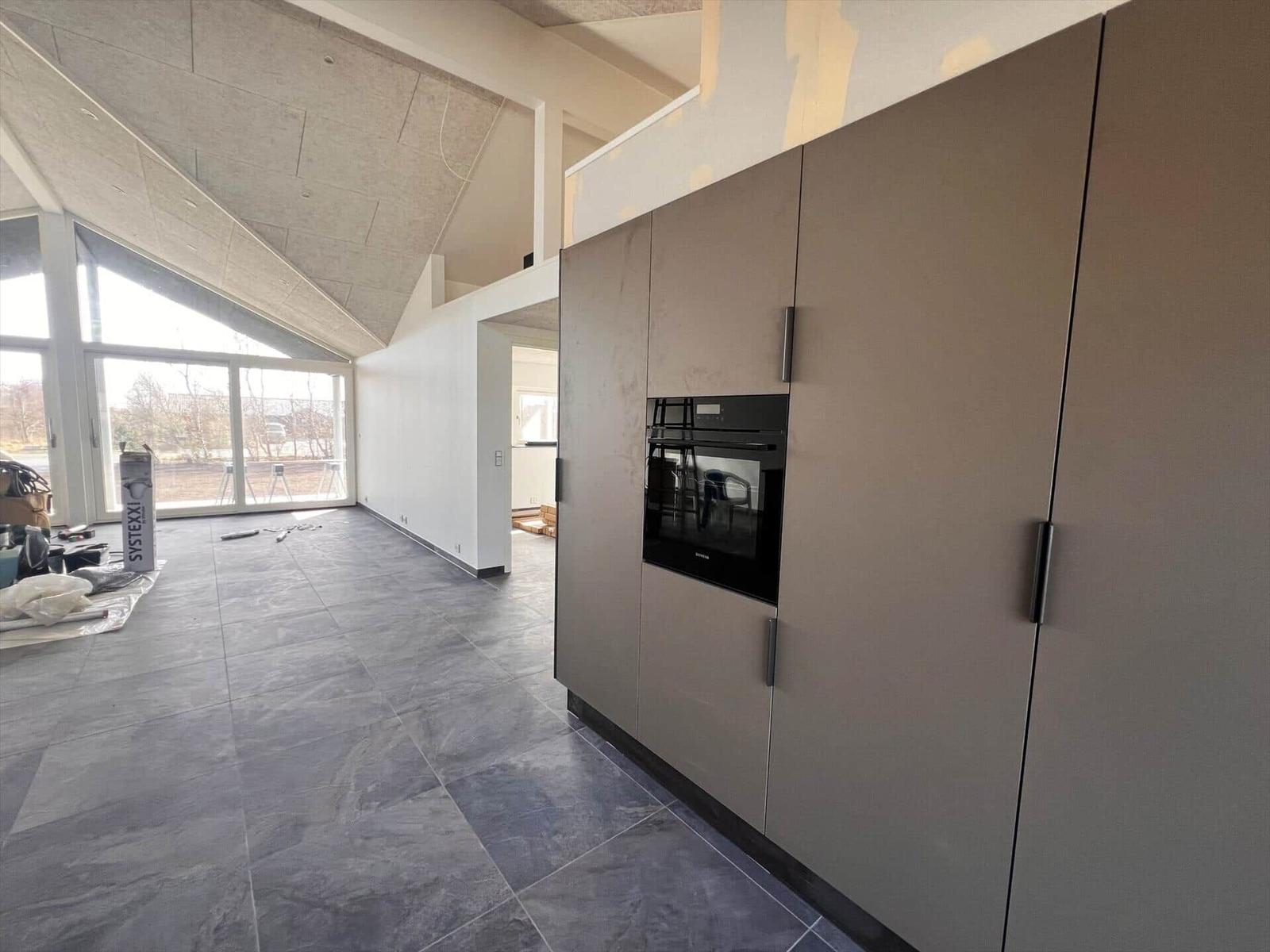 Moderne Küche mit eingebautem Ofen und grauen Fliesenboden.