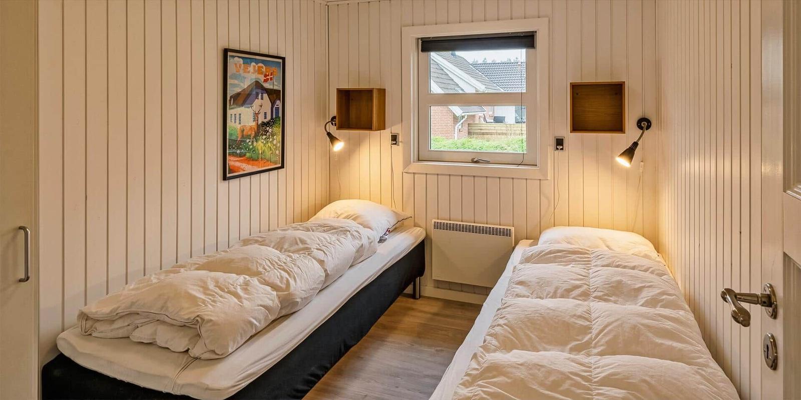 Zwei Einzelbetten in einem Raum mit Holzwänden und Fenster.