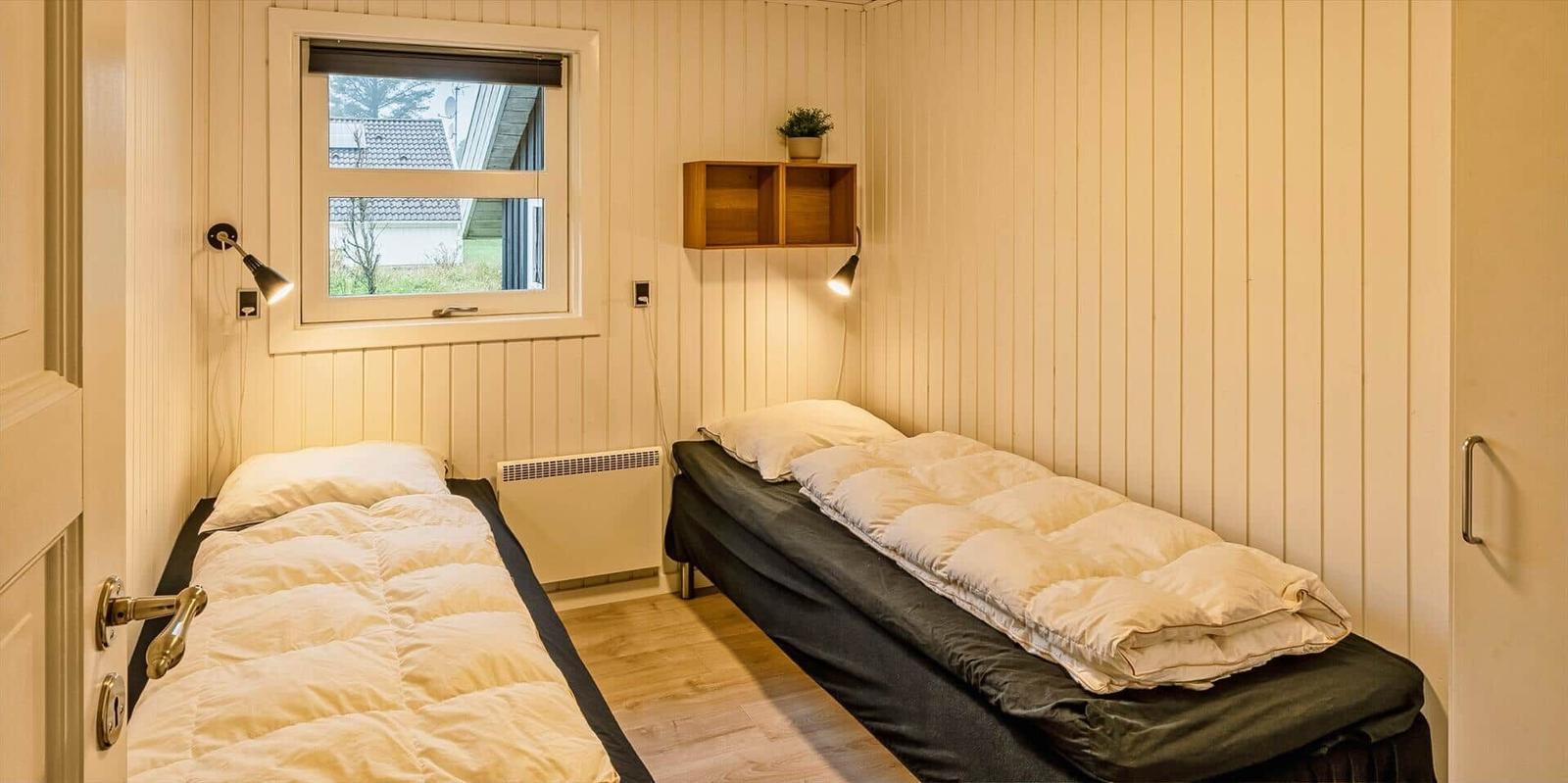 Zwei Betten mit Decken, Wandhalterung und Fenster mit Blick nach draußen.