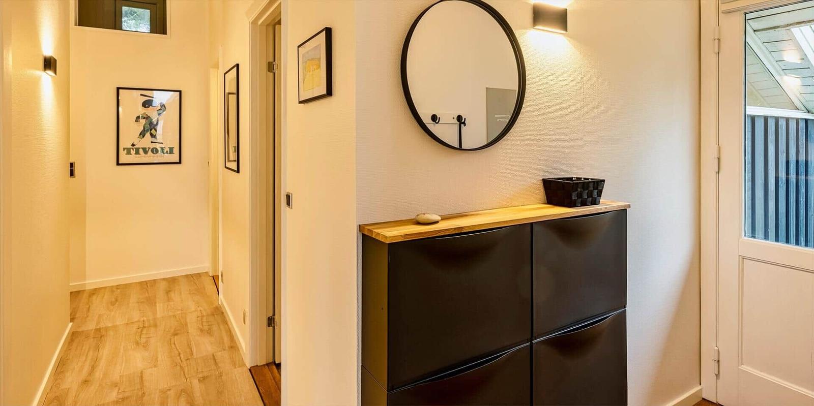 Eingangsbereich mit Schuhschrank, runden Spiegel und Holzboden.
