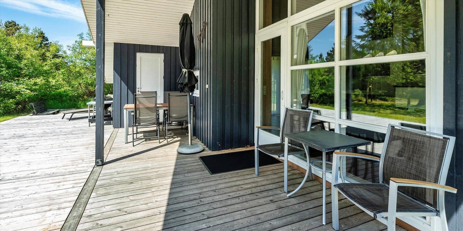 Terrasse mit Tischen und Stühlen, Glasfront und Holzdielen