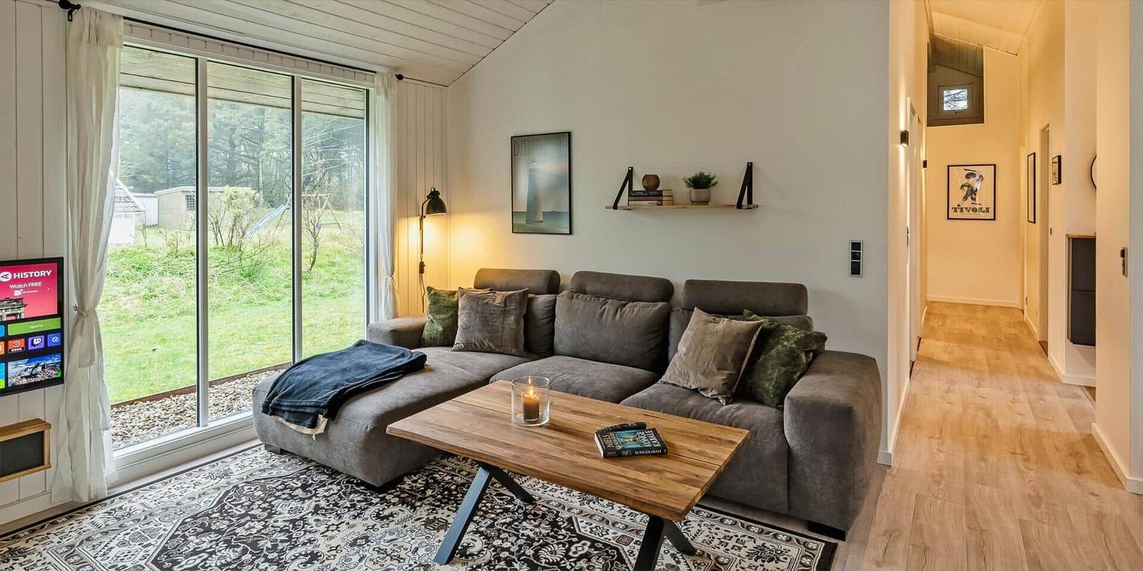 Wohnzimmer mit Sofa, Holztisch und Blick auf Garten