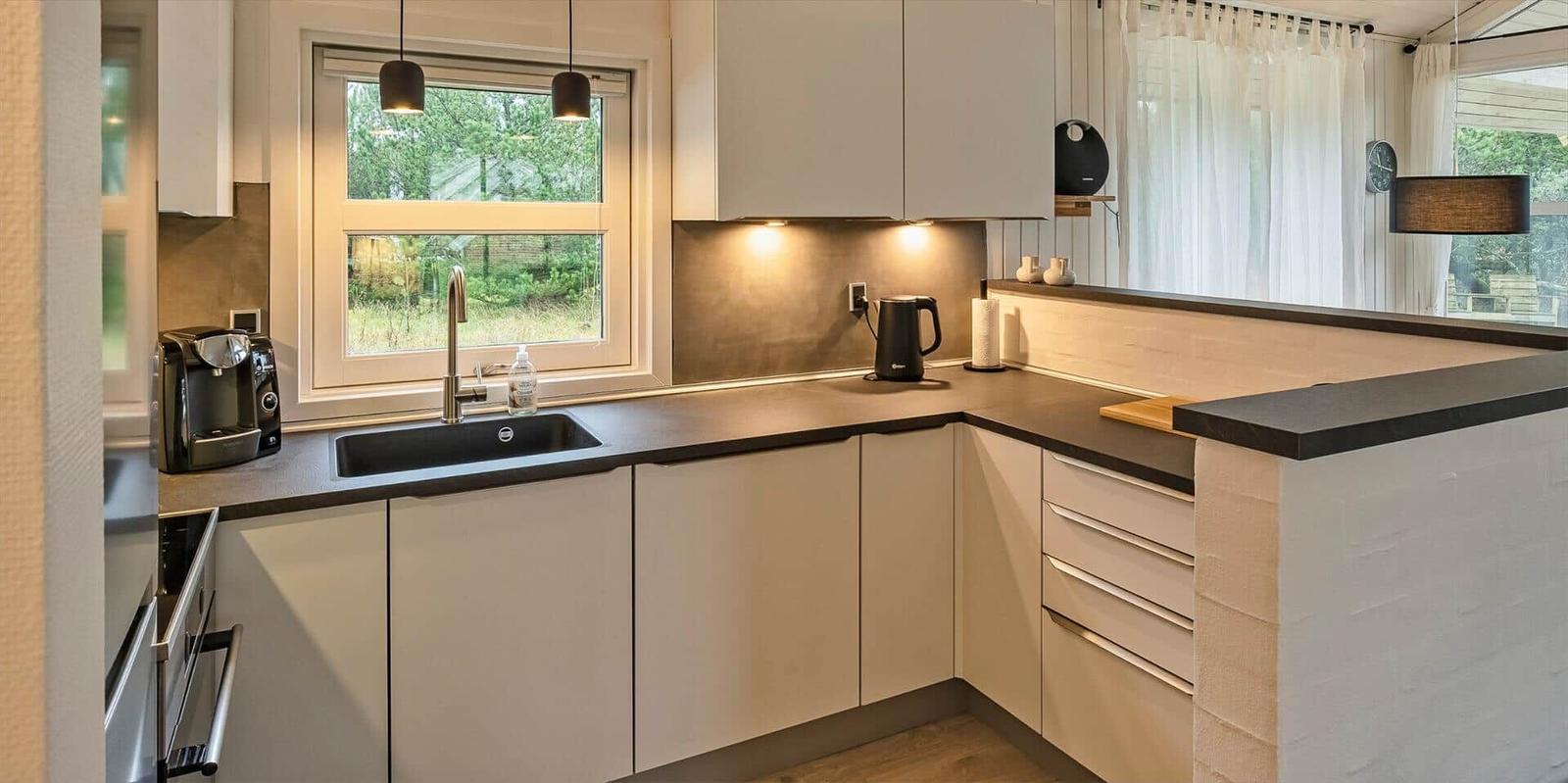 Moderne Küche mit Arbeitsplatte, Spüle und Fenster. 