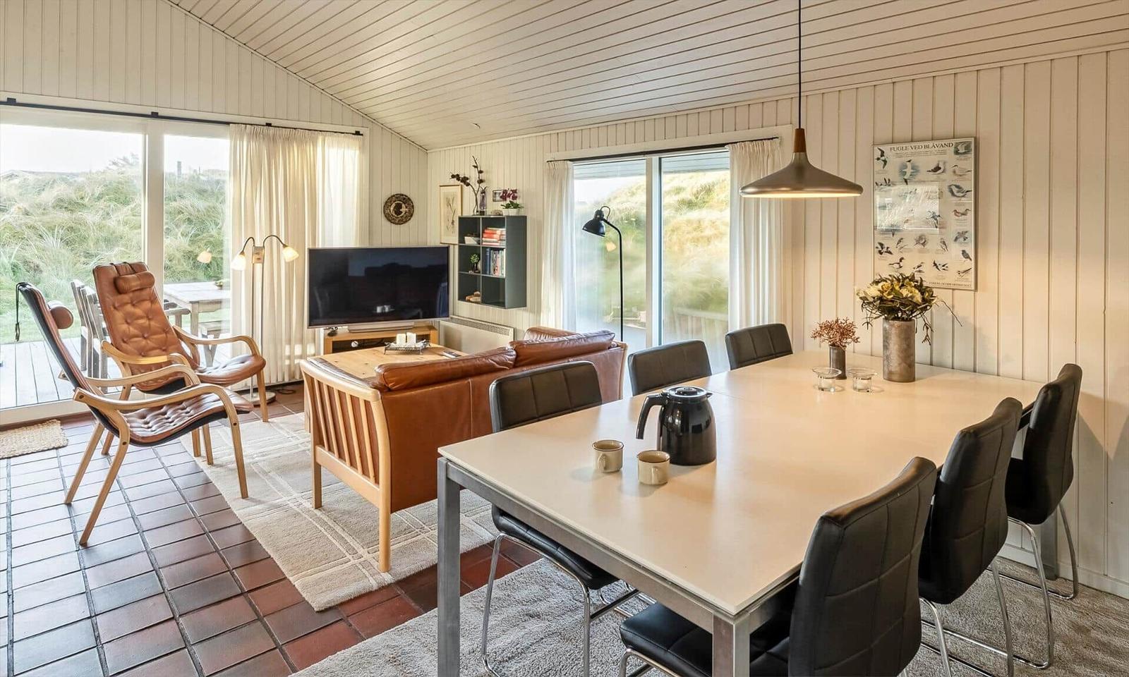 Wohn- und Essbereich mit braunem Sofa, Esstisch und großen Fenstern.