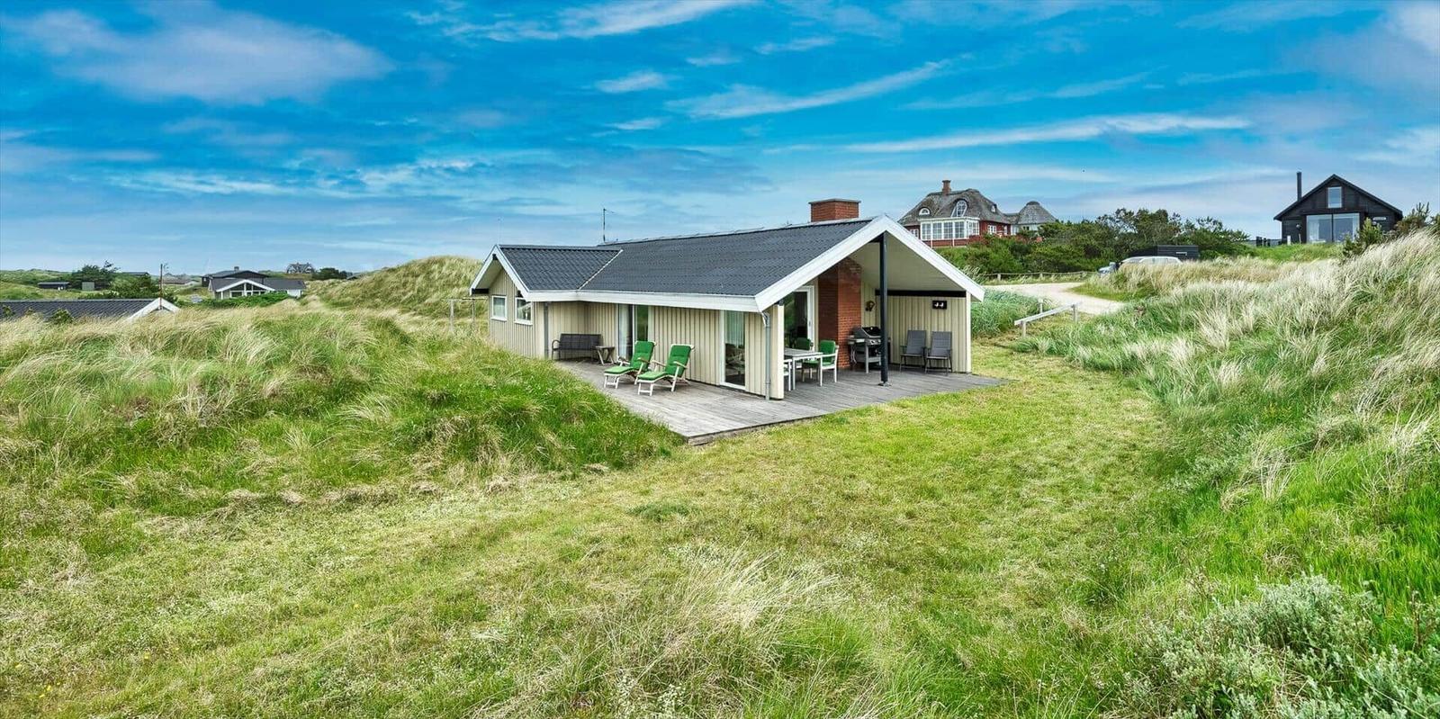 Moderne Strandvilla mit Terrasse und Grillplatz zwischen Dünen.