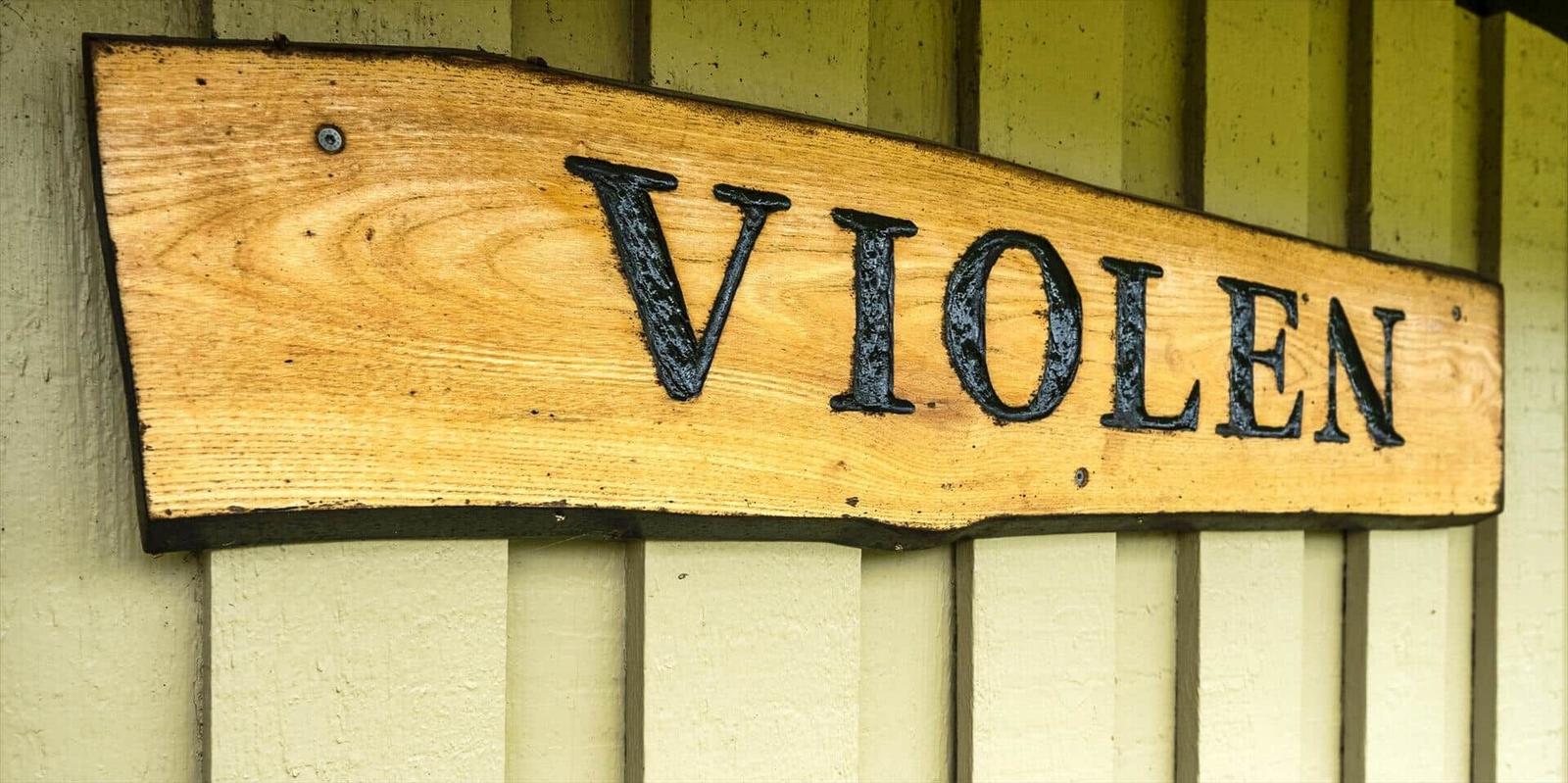 Holzschild mit der Aufschrift VIOLEN an einer Hauswand.