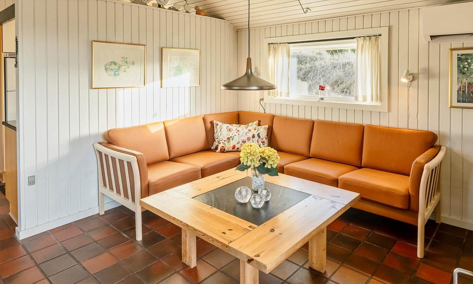 Ein Wohnzimmer mit orangefarbenem Sofa, Holztisch und Fenster.