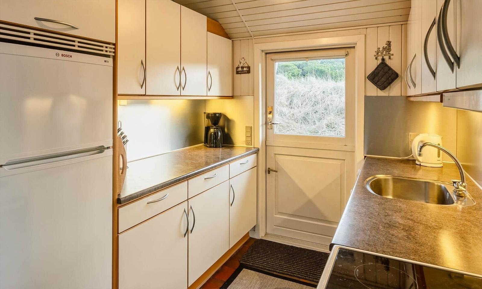 Küche mit Kühlschrank, Spüle und Fenster zur Außenseite.