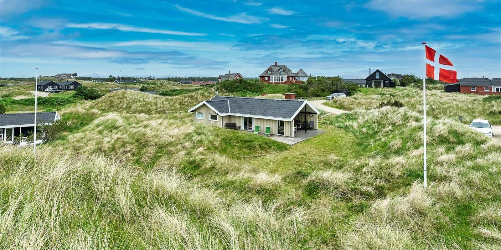Haus auf Dünen mit Flagge und Blick auf andere Häuser.