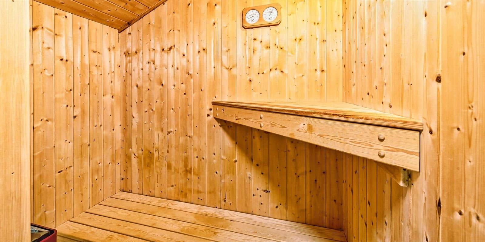 Sauna mit Holzwand, Sitzbank und Temperaturanzeige