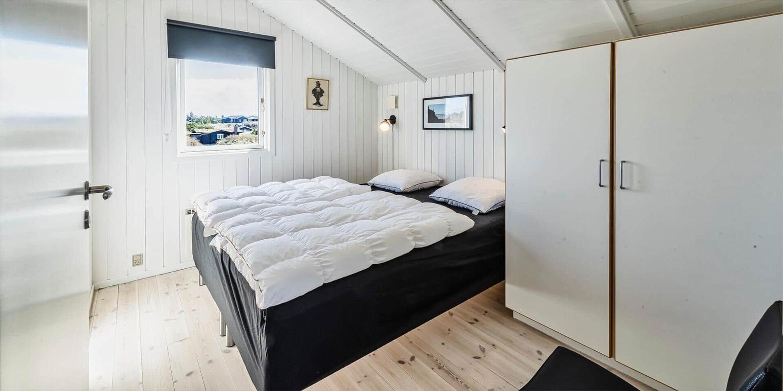 Schlafzimmer mit Bett, Kleiderschrank und Fenster mit Blick.