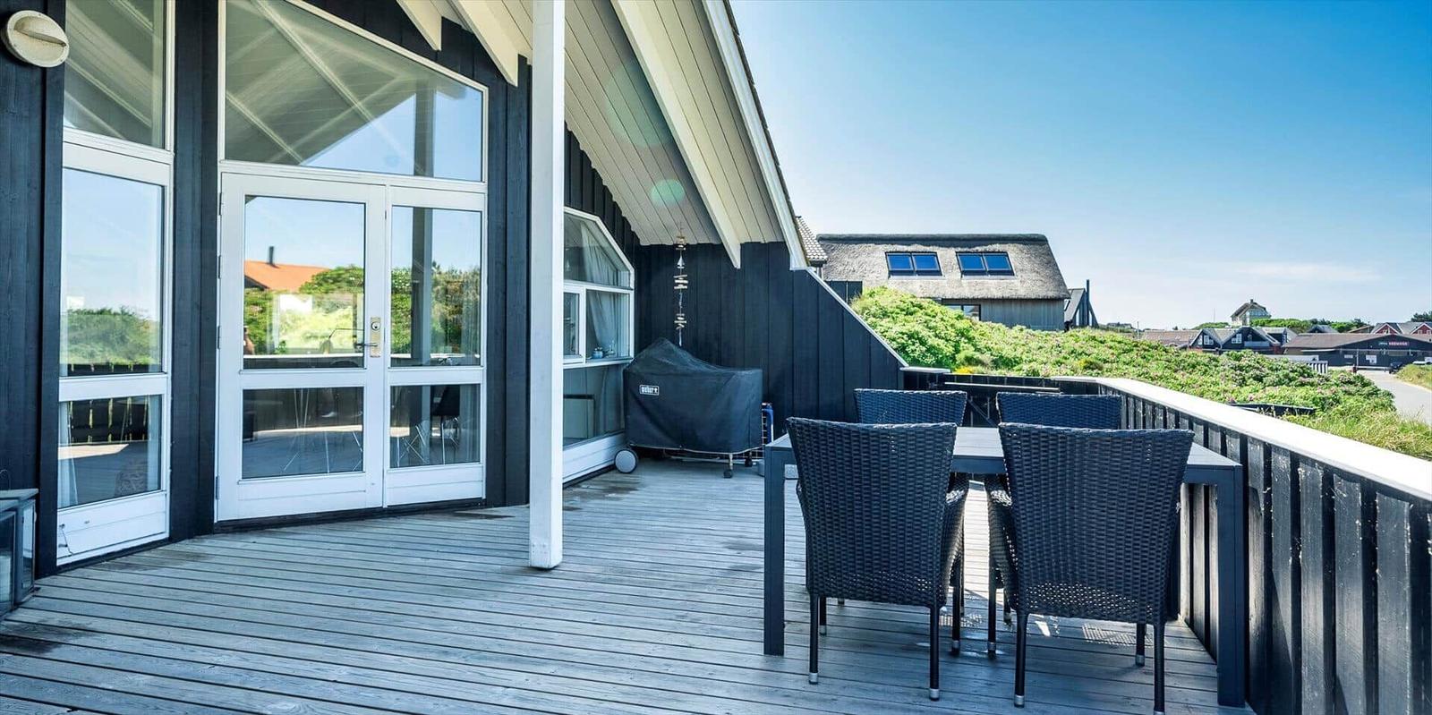 Terrasse mit Tisch und Stühlen, Blick auf Grünfläche und Haus