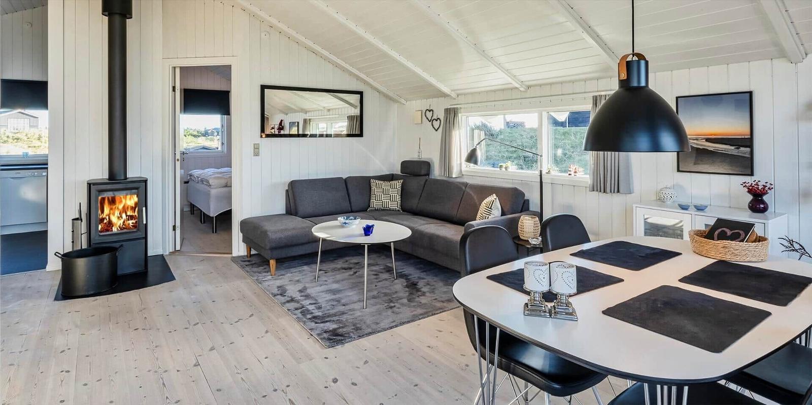 Wohnbereich mit Sofa, Esstisch und Kaminofen. Blick auf Schlafzimmer.