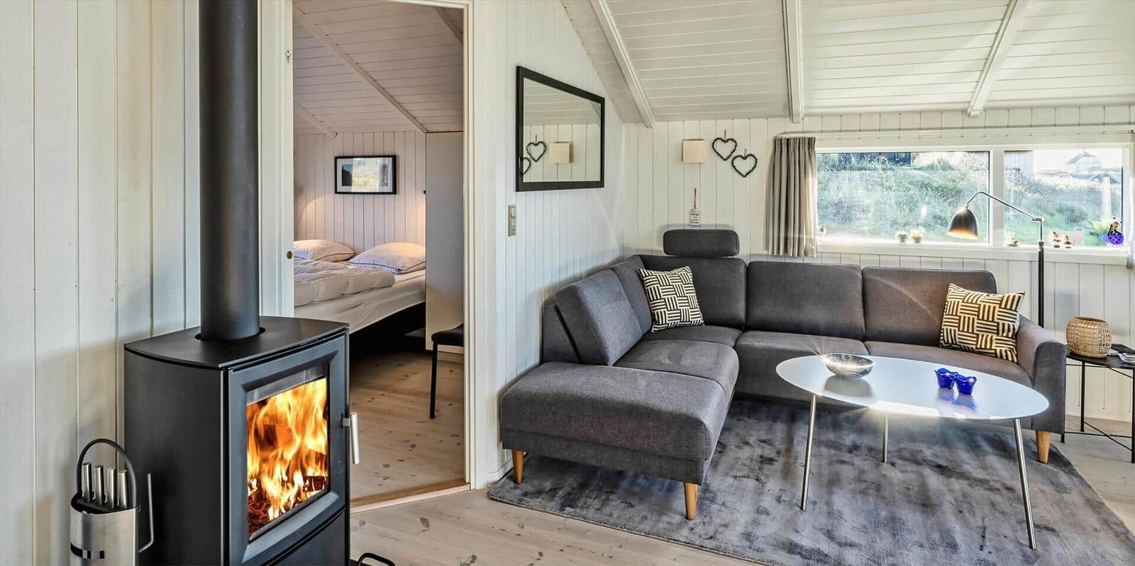 Wohnbereich mit Sofa, Kamin und Blick in Schlafzimmer