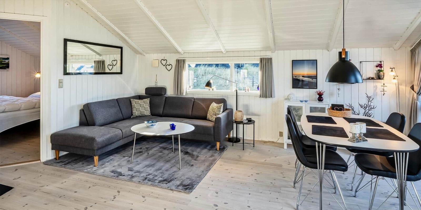 Wohn- und Essbereich mit Sofa, Tisch und Stühlen. Blick in Schlafzimmer.