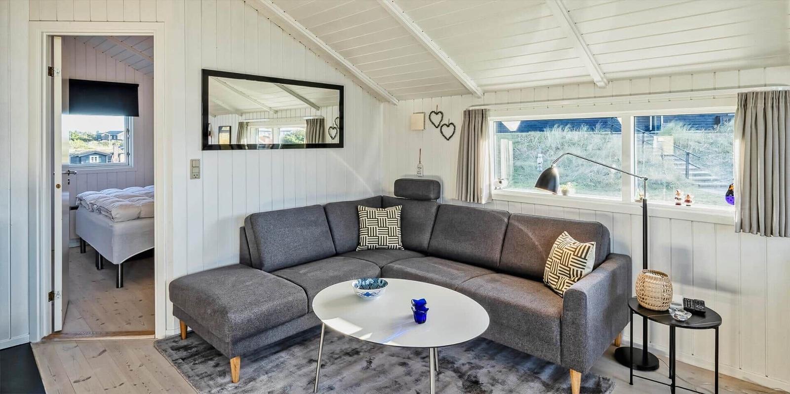Wohnzimmer mit grauem Sofa, runden Tisch und Blick aufs Gras.