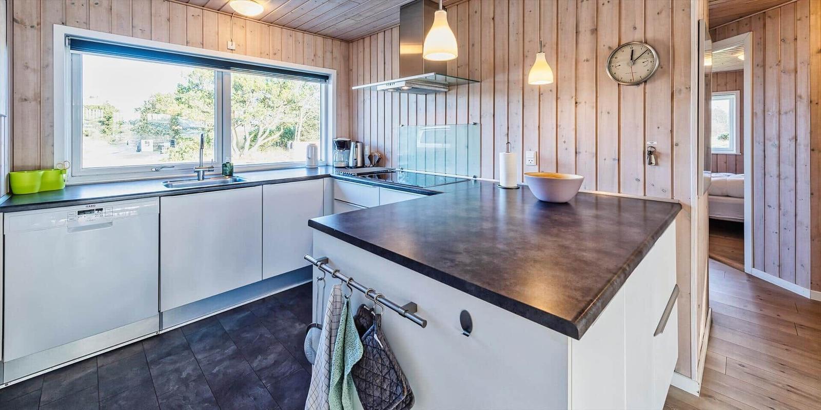 Küche mit Holzwänden, Arbeitsplatte und Fenster zur Aussicht.
