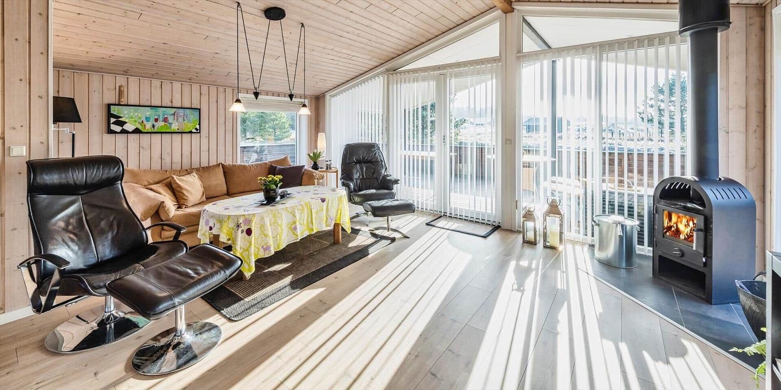 Wohnzimmer mit Sitzgelegenheiten, Esstisch und Kaminofen. Blick auf Balkon.