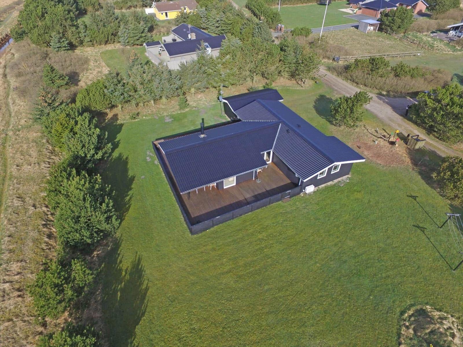 Haus mit Terrasse und Garten. Umgeben von Bäumen und Grasflächen.