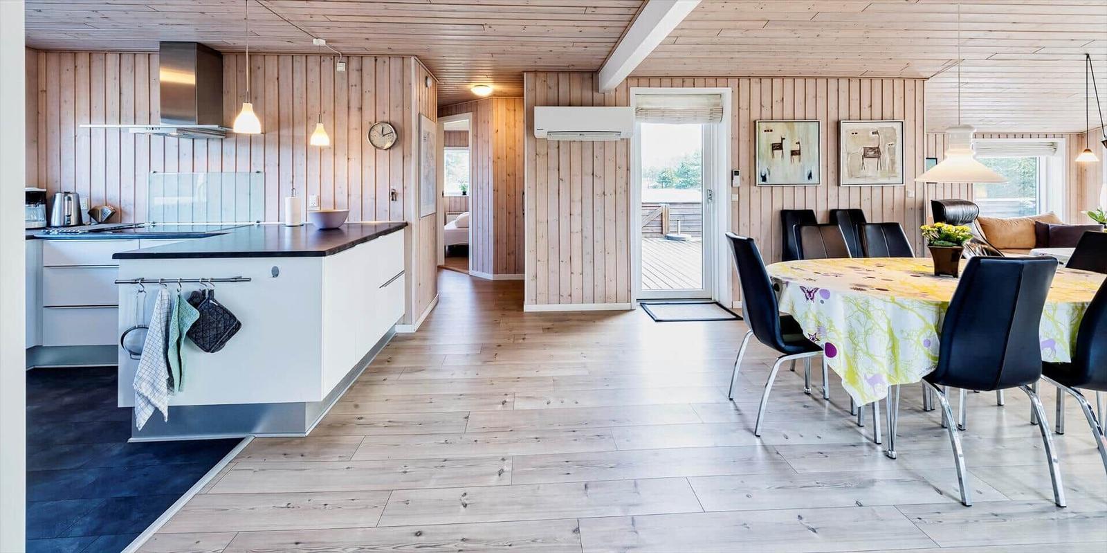 Küche mit Essbereich, Holzwand und Tisch mit Stühlen