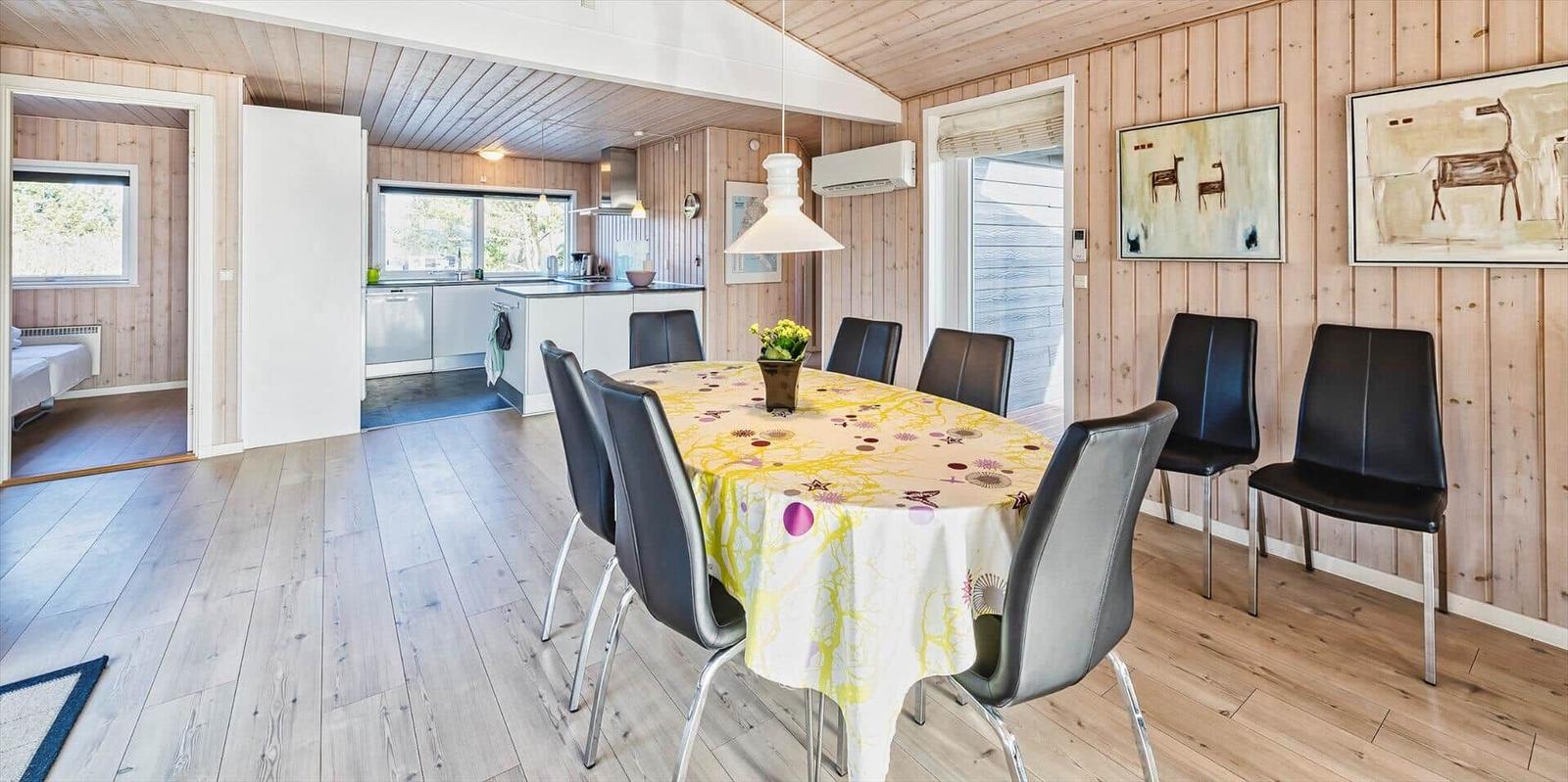 Essbereich mit Tisch, Stühlen und Küchenbereich im Hintergrund.