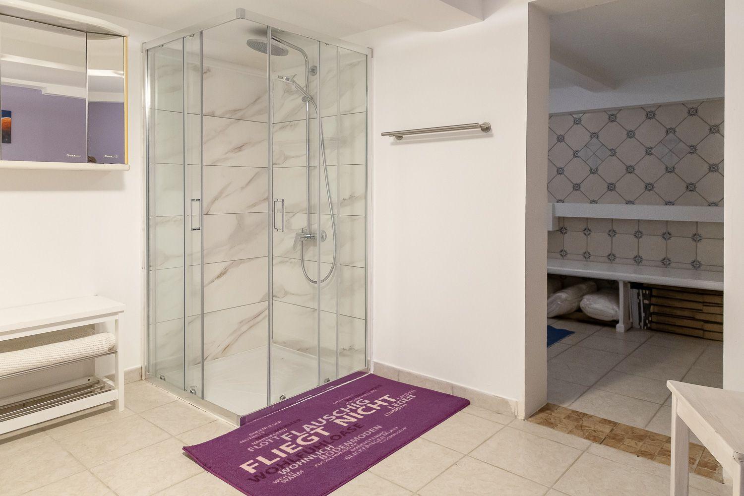 Dusche mit Glaswand, Badematte und Duschbrause