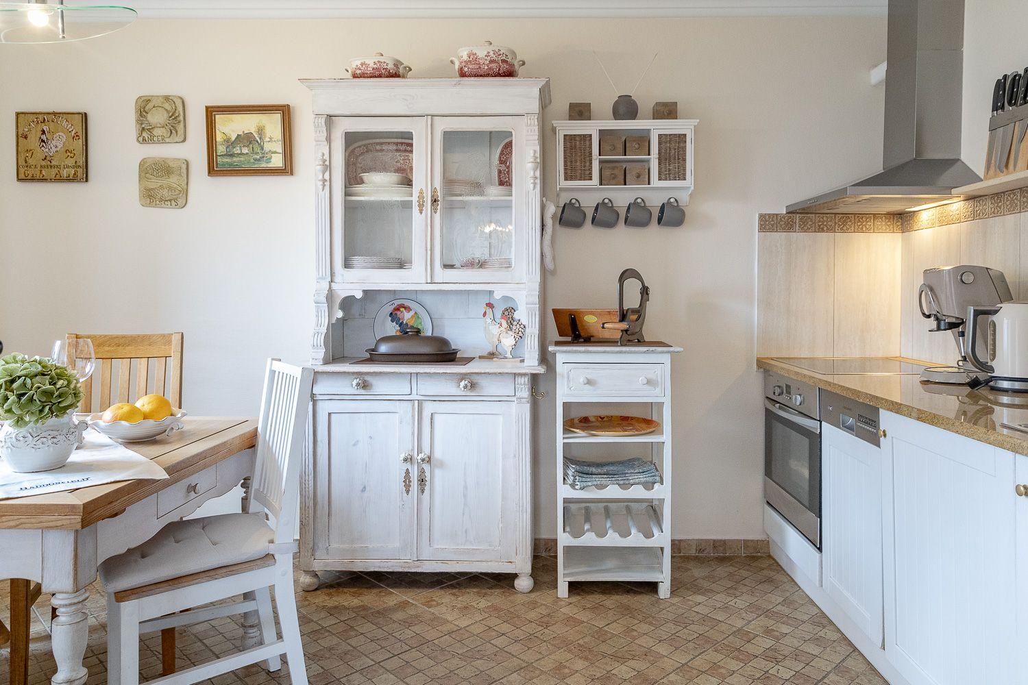 Küche mit weißem Sideboard, Esstisch und moderner Küchenzeile.